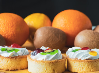 Cakes with whipped cream and slices of fruit, kiwi and oranges