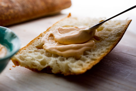 Close up of homemade sriracha mayo being spread on bread