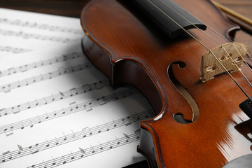 Fototapeta premium Beautiful violin and note sheets on table, closeup