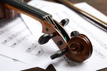 Fototapeta premium Beautiful violin and note sheets on table, closeup