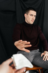 Serious man sitting and refusing the protective medical mask giving to him