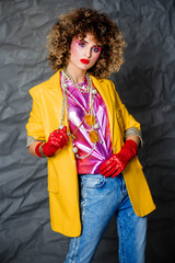 Portrait of a girl in a yellow jacket and blue jeans with afro hair of the eighties, disco era....