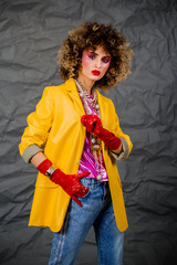Portrait of a girl in a yellow jacket and blue jeans with afro hair of the eighties, disco era....