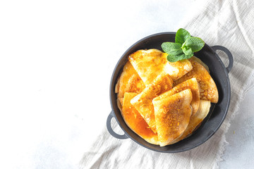 Crepes with Orange Sauce in a cast iron pan. Traditional French crepe Suzette with orange sauce.