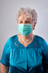 Old woman coronavirus helper. Old lady isolated at home. Home activities. Stay at home. Grandmother sewing face protection masks during quarantine. Old lady wearing protection mask. COVID-19 concept.