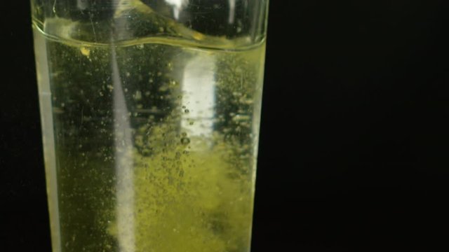 Aspirin Dropping into Glass of Water and Dissolving