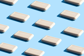 Pattern of pieces of solid soap on a blue background with trendy sunlight. Wash your hands. Soap against bacteria and viruses. Compliance with hygiene and sterility to combat coronavirus.