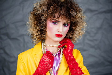 Portrait of a girl in a yellow jacket and blue jeans with afro hair of the eighties, disco era....