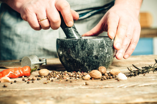 male hands crush spices in a mortar