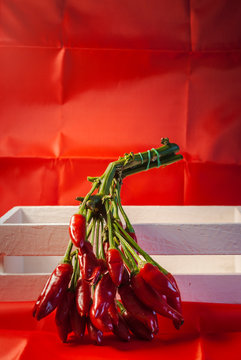 Bunch of hot peppers on a white box and red background