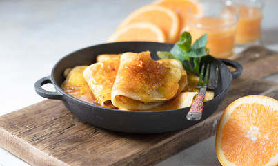 Crepes with Orange Sauce in a cast iron pan. Traditional French crepe Suzette with orange sauce.