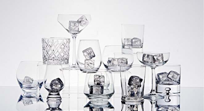 Variety of glasses with ice cubes on table