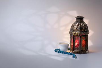 Ramadan Lantern, rosary beads and Arabic coffee, with arabesque shadow on background.