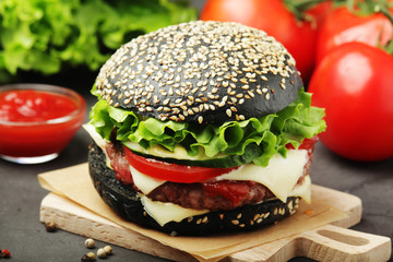 A black burger with vegetables and beef meat