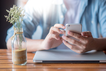 Male hand using smartphone while working with laptop computer at home. Relaxing time with entertainment and social media mobile app. Modern device for global communication.  Internet of things concept