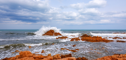 Wild and suggestive east coast of Sardinia. 
Beach with red porphyry rocks in the immense Mediterranean scrub of Ogliastra, Sardinia, Italy