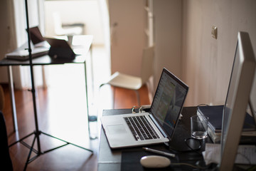 Postazione di lavoro dentro casa con computer portatile e monitor sopra un tavolo 