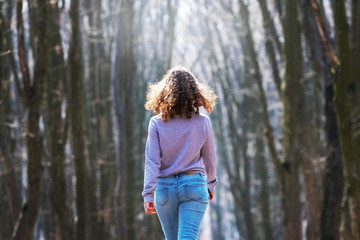 Young girl walking in spring forest, early spring in forest