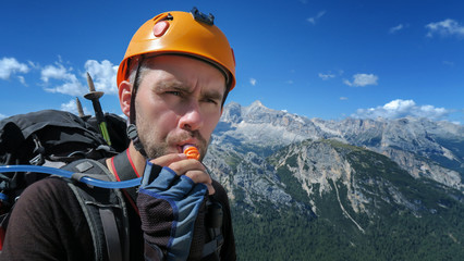 A thirsty tourist drinks water through a tube against the backdrop of an amazing panorama of the...