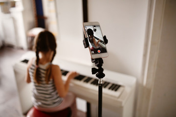 child plays digital piano and records video phone