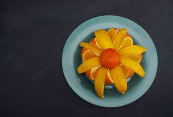 Orange, lemon and kiwi flower. Blue plate. Gray background. Vitamins for spring. 
