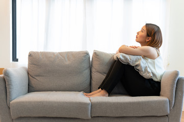 Obraz premium Depression and sadness concept,Young asian woman covering her face sitting on sofa in home.
