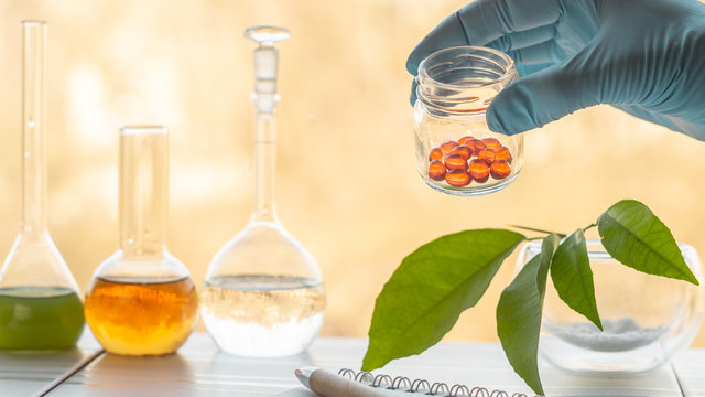 Hand of a pharmacist holds a jar with vitamins in the laboratory