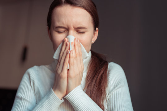 Cough In Tissue Covering Nose And Mouth When Coughing. European Woman Sick With Flu At Home.