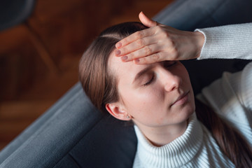 Sick girl at home with headache feeling faint vertigo holding head in pain with fever and migraine.