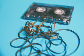 Closeup of a cassette tape from the 80s and 90s with blue background and twisted tape