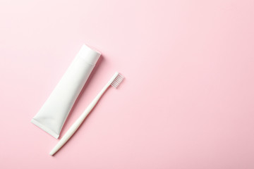 Toothbrush and toothpaste on pink background, space for text