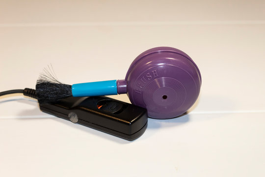 On a white background are devices for the camera - a remote shutter button and a brush for cleaning the lens.