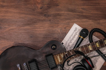 guitar and headphones, notes and microphone on a wooden background, electric guitar, compose music,...
