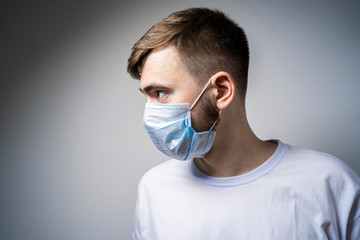 A man in a medical mask looks away. Self isolation