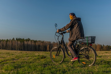 Fototapeta na wymiar Young man on black electric bike in spring color evening