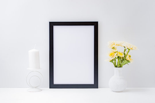 Home interior with decor elements. Mockup with a black frame and flowers in a vase on a light background