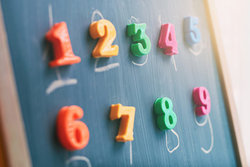 Learning numbers on a blackboard with colorful magnets and handwriting on blackboard during...