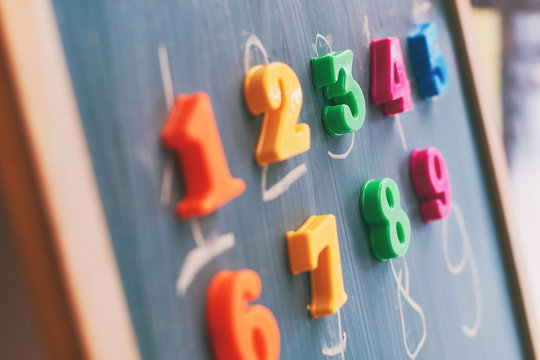 Learning numbers on a blackboard with colorful magnets and handwriting on blackboard during homeschooling at quarantine