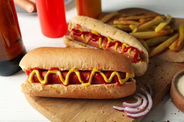 Tasty hot dogs, beer and sauces on white wooden background