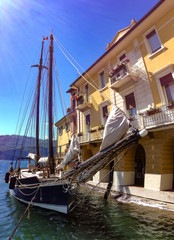 Fototapeta na wymiar Segelboot liegt an einer schönen Ortschaft am Gardasee in Italien