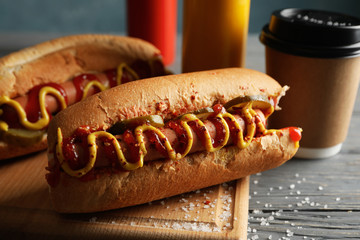 Tasty hot dogs, coffee and sauces on wooden background