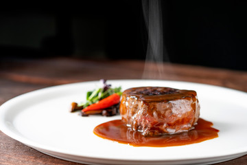 Grilled beef tenderloin steak on a white platter is served with demiglas sauce