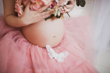 Male and female hands on a pregnant belly. The girl in the pink dress.