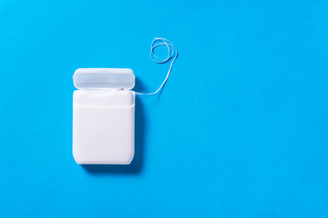 Dental floss in white plastic box on blue background