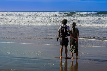 Junge Menschen am Strand blicken auf das Meer hinaus