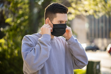 Virus mask man wear face protection in prevention for coronavirus. Man walking on the street with green tree background