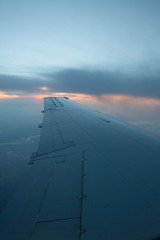 Naklejka na ściany i meble cloudy sunset sky over plane wing