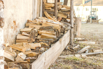 In the village, chopped firewood and in the background a tractor stands with a two-story house