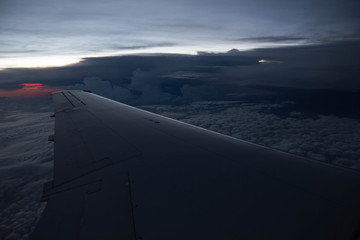 Naklejka na ściany i meble cloudy sunset sky over plane wing