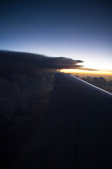 cloudy sunset sky over plane wing with thunderhead